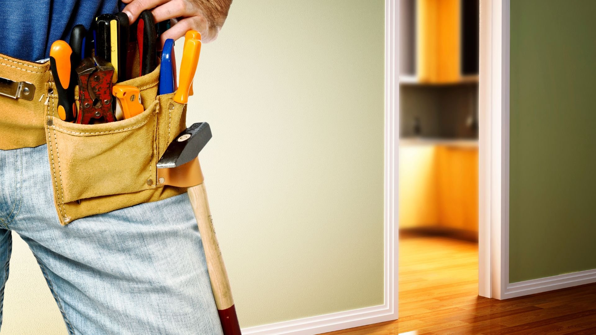Handyman with tool belt standing near wall, ready for home repair