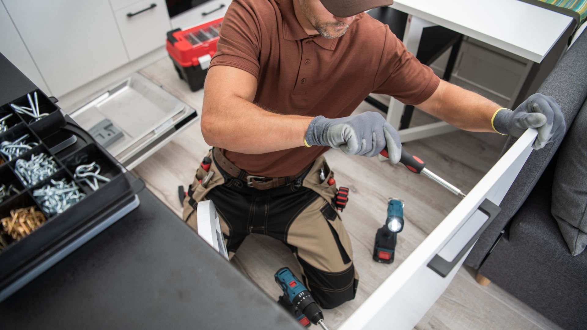 Craftsman with tool belt installing drawer in workshop with power tools
