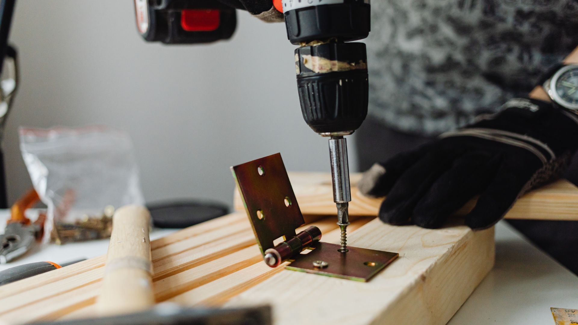 Drilling metal hinge onto wooden surface with power drill