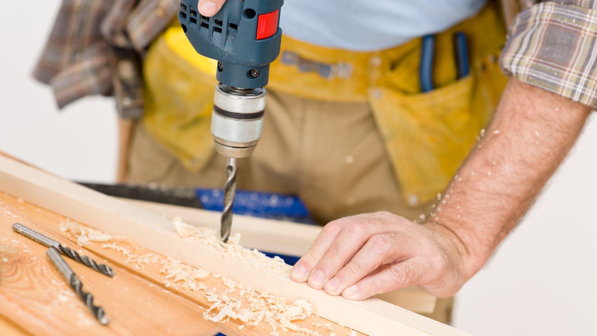 Person drilling into wood with power drill, wood shavings visible