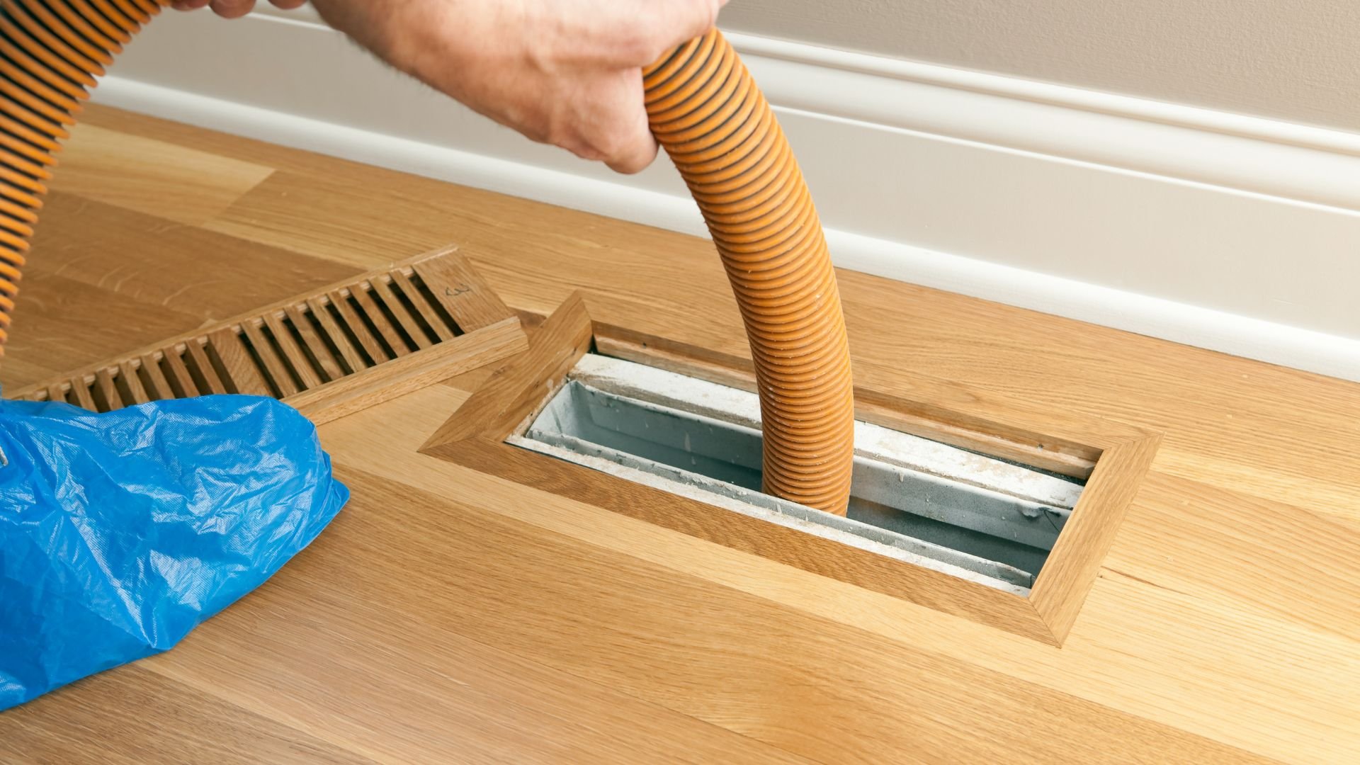 Vacuum hose cleaning central vacuum system inlet on wooden floor