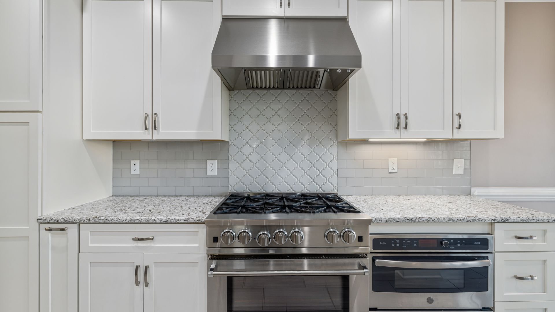 Modern white kitchen with stainless steel appliances and arabesque backsplash